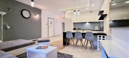 a living room and kitchen with a clock on the wall at VIP Apartamenty Stara Polana 2 in Zakopane