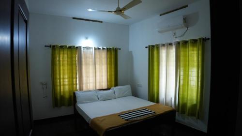 um pequeno quarto com cortinas verdes e uma cama em Thas apartment em Alwaye