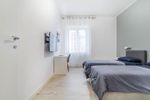 2 łóżka w pokoju z białymi ścianami i drewnianą podłogą w obiekcie Casaballi Milano MM3 Trilocale w Mediolanie