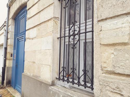 a iron barred window on a building with a blue door at Home Sweet Zen, appartement près de la gare St Jean in Bordeaux