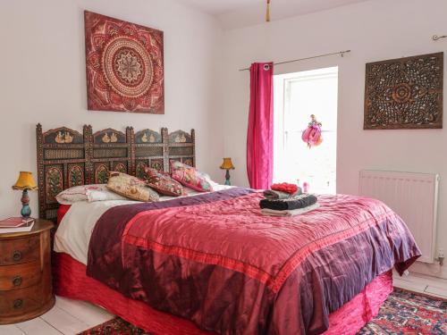 a bedroom with a bed with a red blanket and a window at Wonderland Cottage in Cupar
