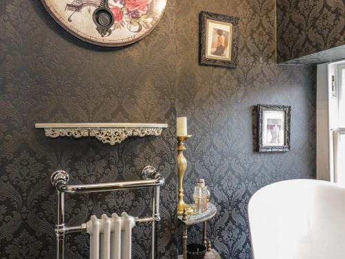 baño con radiador y reloj en la pared en Wonderland Cottage, en Cupar