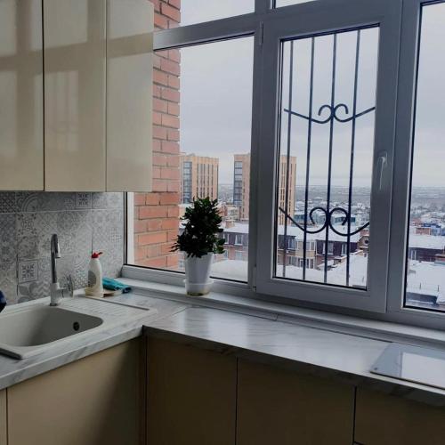 a kitchen with a view of a city from a window at ВИП апартаменты 1+1 в Жана Кала, город Костанай in Kostanay