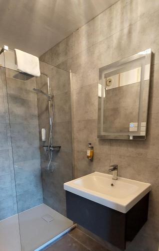 a bathroom with a sink and a shower with a mirror at Logis Le Prieuré in Locronan