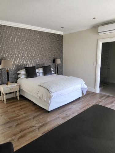 a bedroom with a white bed and a wall at The Grandstancia in Cape Town