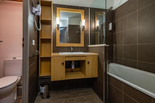 een badkamer met een wastafel, een toilet en een spiegel bij Solaise in Val dʼIsère