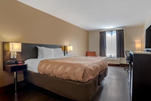 a hotel room with a large bed and a desk at Quality Inn Phenix City Columbus in Phenix City