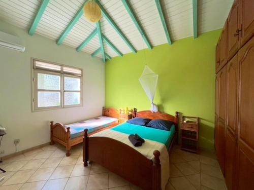 um quarto com 2 camas num quarto com paredes verdes em Appartement de 4 chambres avec piscine partagee jardin clos et wifi a Le Gosier a 1 km de la plage em Le Gosier