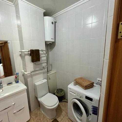 uma casa de banho com uma máquina de lavar roupa e um WC em Однокомнатная в новом районе Жана Кала em Qostanay