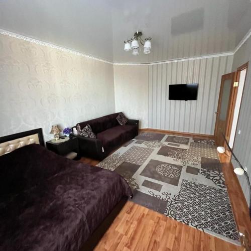 uma sala de estar com uma cama e um sofá em Однокомнатная в новом районе Жана Кала em Qostanay