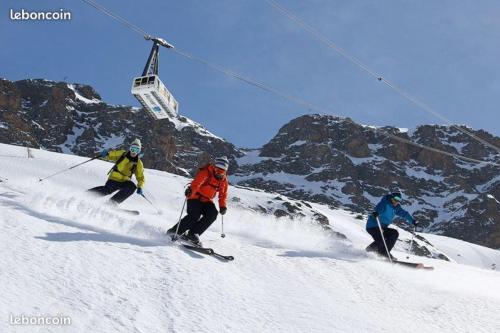 three people are skiing down a snow covered mountain at Le Perce Neige in Vaujany