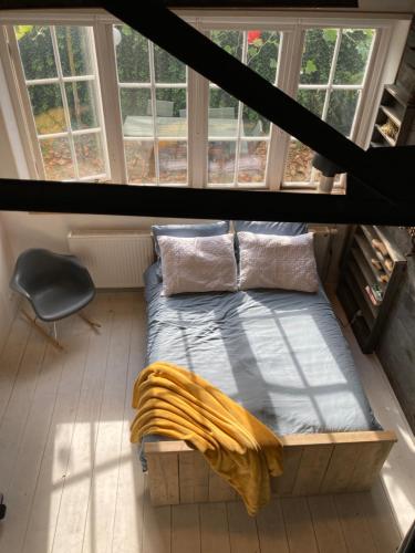 een bed in een kamer met ramen bij Mooi appartement in Werkplaats in Kampen