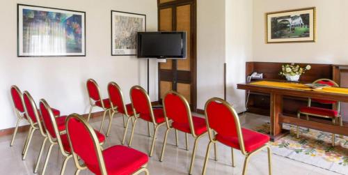 a conference room with red chairs and a desk at Hotel Il Chiostro by LVG Hotel Collection in Verbania