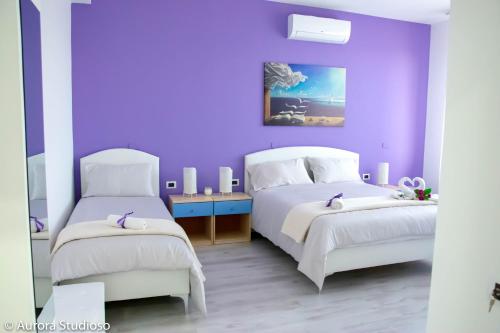 Dormitorio púrpura con 2 camas y pared púrpura en B&B L'incanto degli Artisti en Caltagirone