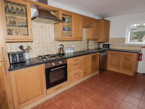 a kitchen with wooden cabinets and a stove top oven at The Chapel in Merthyr Tydfil