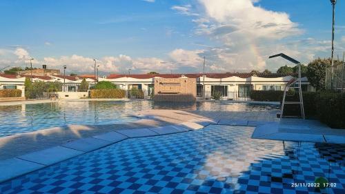 a swimming pool with blue tiles in front of buildings at Agradable casa con piscina en tierra caliente in Flandes