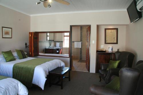 a hotel room with a bed and a bathroom at Queen Manor Boutique Guest House in Graaff-Reinet