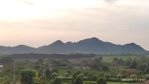 a view of a field with mountains in the background at บ้านไร่โฮมเทล ณ ปากช่อง in Ban Nong Takhain