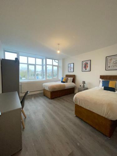 a bedroom with two beds and a desk and windows at Flitwick Luxury Apartments in Flitwick