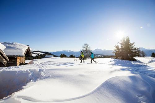 two people skiing down a snow covered slope at Granpanorama Hotel StephansHof in Villandro