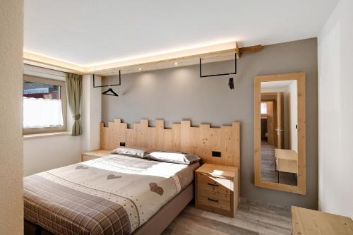 een slaapkamer met een groot bed en een spiegel bij Petalo Rosina's Home in Livigno