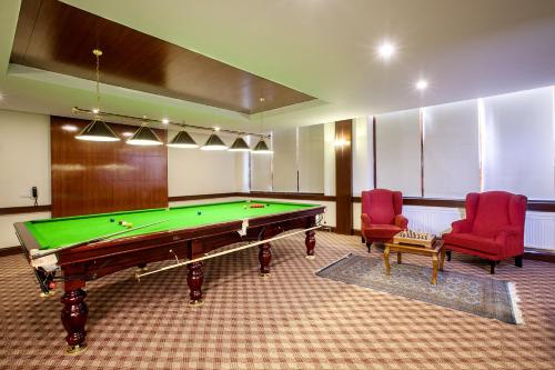 a room with a pool table and two red chairs at The Grand Dragon Ladakh in Leh