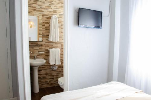 baño con aseo y TV en la pared en Hotel Valles en Mar del Plata