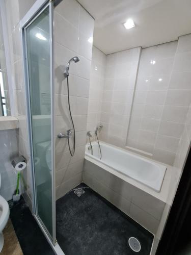 a bathroom with a shower and a tub and a toilet at St. Moritz Apartement Royal 2br in Jakarta