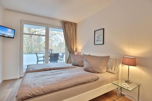 sypialnia z łóżkiem i balkonem z widokiem na okolicę w obiekcie Strandglück Haus A Strandglück Appartement 12A w mieście Scharbeutz