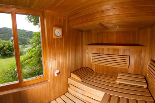 an empty sauna with a clock and a window at Ferienhof Obergasser und Bergblick in Weissensee