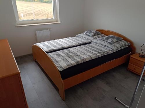 1 dormitorio con cama con marco de madera y ventana en Widok, en Ostróda