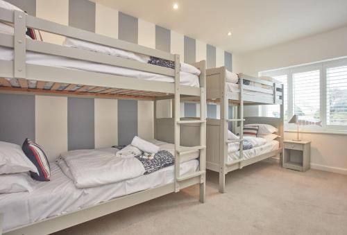 a bedroom with two bunk beds and a window at 5 The Sands in Polzeath