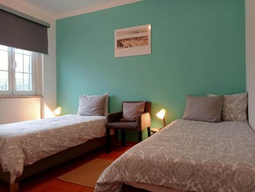 a bedroom with two beds and a chair in it at casal do melro in Ericeira