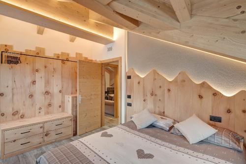 a bedroom with a bed and a wooden wall at Gemma Rosina's Home in Livigno
