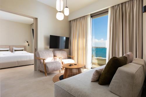 a hotel room with a couch and a bed and a window at KALES SEA VIEW SUITES in Ierapetra