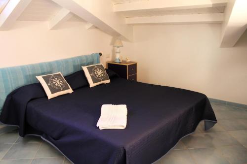 una camera da letto con un letto blu e cuscini sopra di L’attico del capitano: loft con terazza sul mare a Marina di Caronia