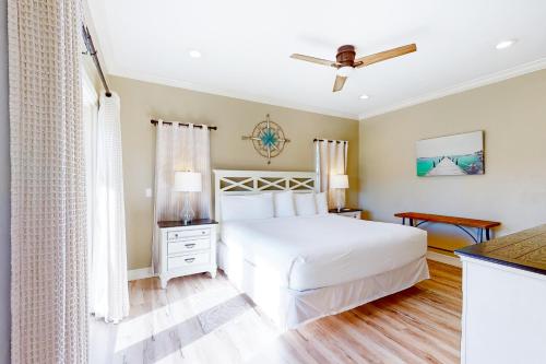 a bedroom with a white bed and a ceiling fan at Serenity Now in St. George Island