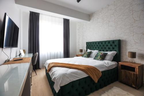 a bedroom with a large bed with a green headboard at Touchdown Apartment near Bucharest Airport in Otopeni