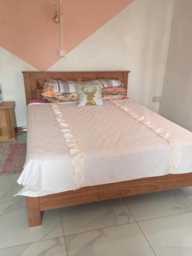 a bed in a room with a wooden frame at tina house in Bel Ombre