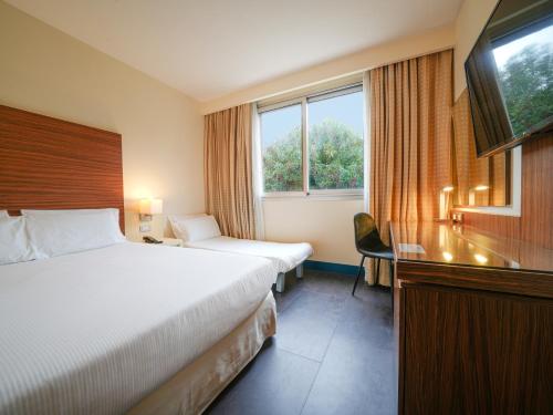 a hotel room with two beds and a television at La Meridiana Bleisure Hotel in Perugia