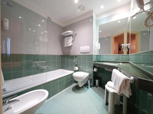 a bathroom with a toilet and a tub and a sink at La Meridiana Bleisure Hotel in Perugia