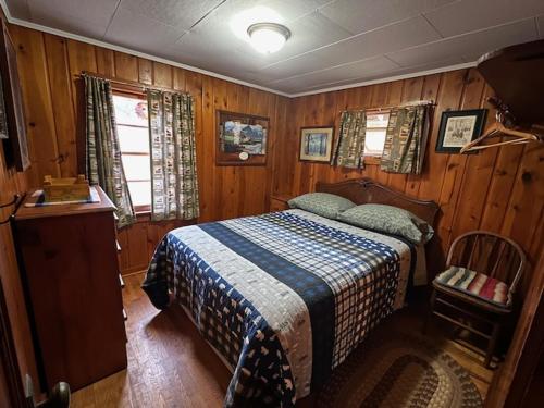 una camera con un letto in una stanza con pareti in legno di Red Tree Resort LLC a Phillips