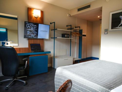 a room with a bed and a desk and a computer at La Meridiana Bleisure Hotel in Perugia