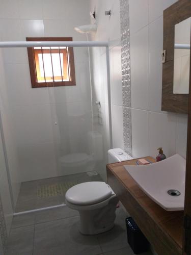 een badkamer met een toilet, een wastafel en een douche bij Recanto da Praia Paraíso in Torres