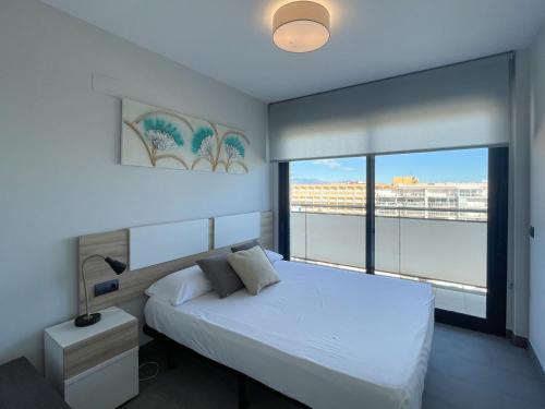 a bedroom with a white bed and a large window at Apartamentos la Volta Aguamarina in Peñíscola
