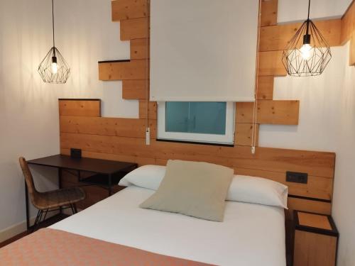 a bedroom with a bed and a desk and a window at Pensión La Perla in Donostia-San Sebastián