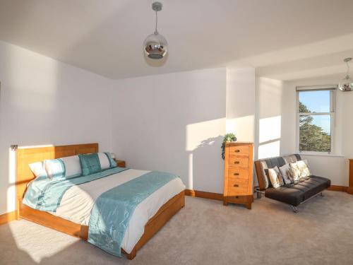 a bedroom with a bed and a chair and a window at Bryn Mel Manor Straits View in Menai Bridge