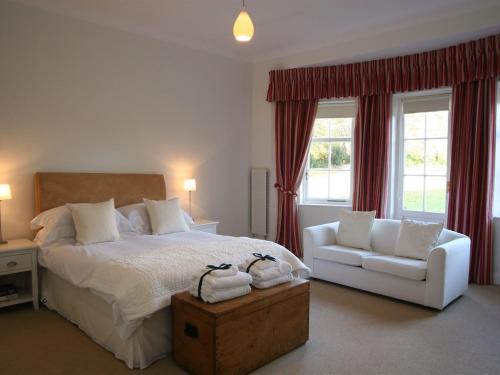 a bedroom with a white bed and a white chair at The Coach House at Stewart Hall in Rothesay