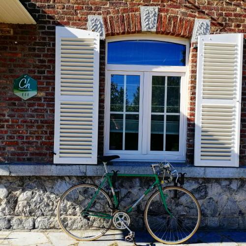 a green bike parked in front of a brick house at Les2sources Bike-B&B in Rochefort