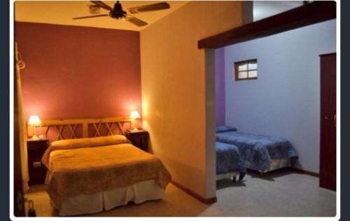1 dormitorio con 2 camas y ventilador de techo en Mirasoles Hotel en Mina Clavero